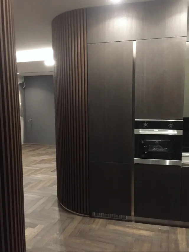 Curved slatted wall with built-in kitchen units